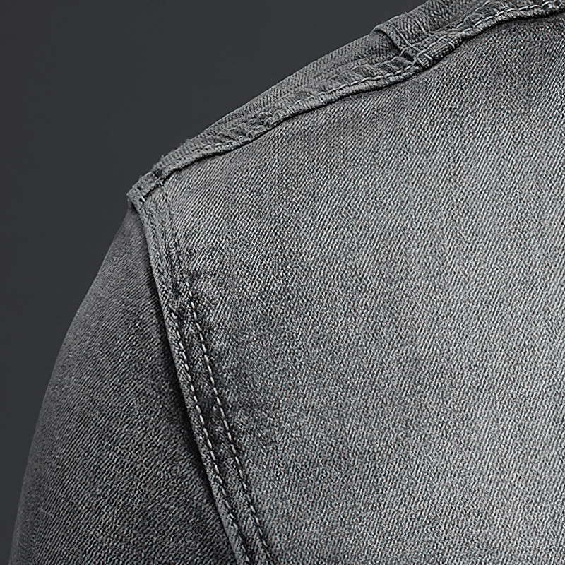 Close-up of the shoulder seam on a men's gray slim fit denim jacket, showcasing quality denim fabric.