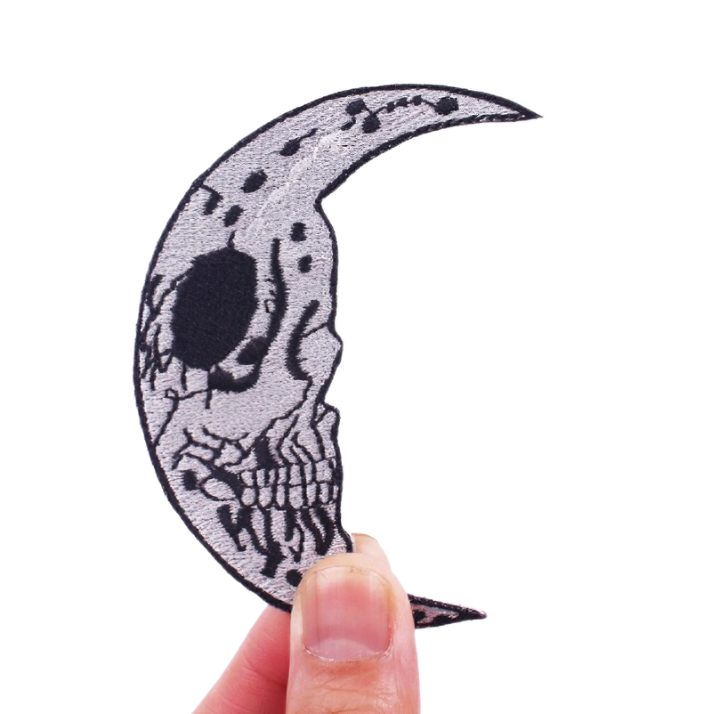 Skull moon patch held in hand, Gothic accessory for clothes, unisex design in stylish rock style.