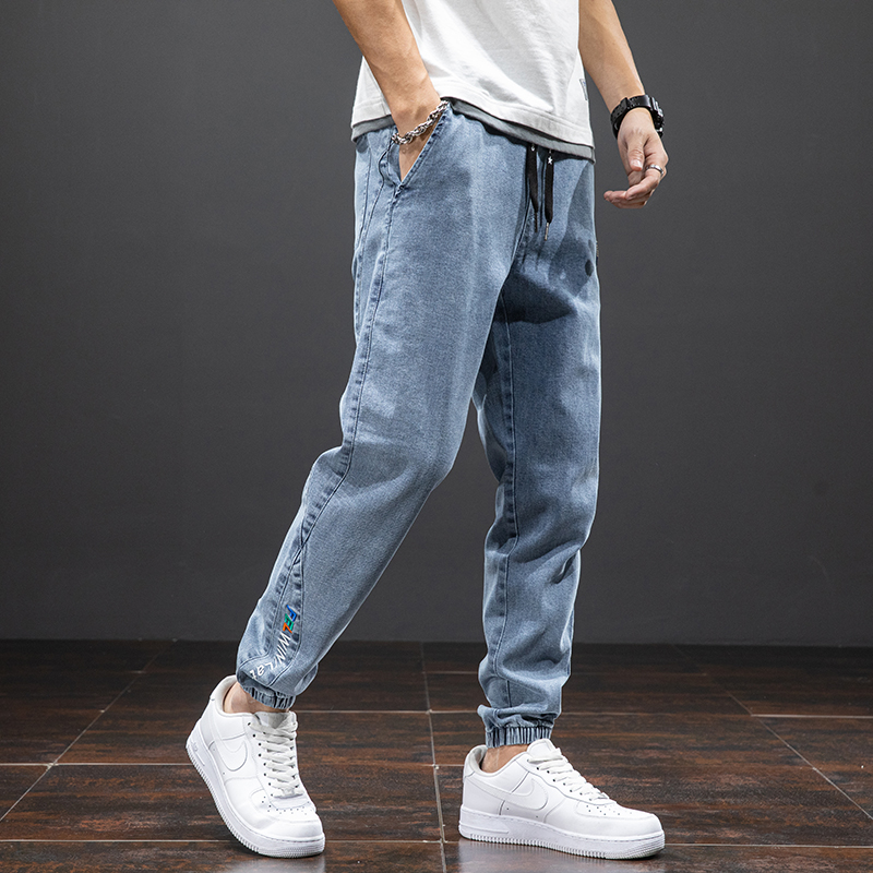 Men's denim cargo pants in loose fit, styled with white sneakers and casual tee, showcasing trendy comfort in blue.