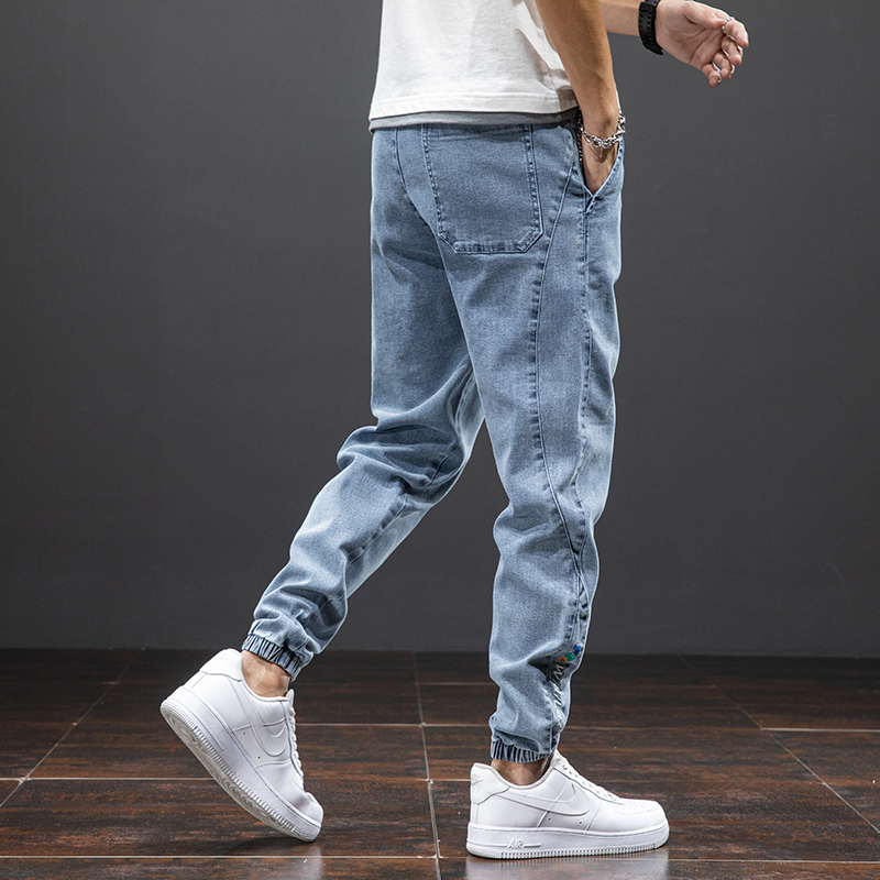 Men's loose fit denim cargo pants in light blue, showcasing casual style and comfort with elastic cuffs.