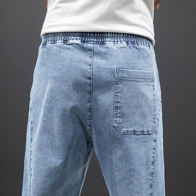 Back view of denim cargo pants featuring an elastic waistband and pocket detail in a light blue color.