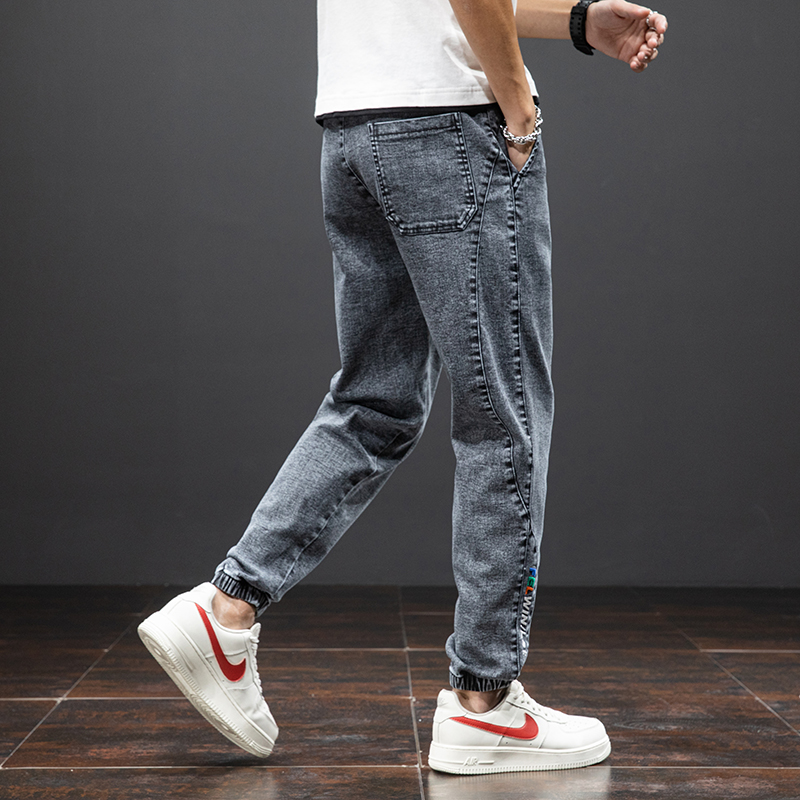 Men's loose denim cargo pants in dark gray featuring elastic waistband and casual style, paired with trendy sneakers.