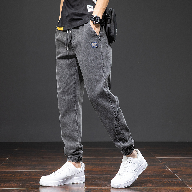 Men's denim cargo pants with elastic waist, styled casually with sneakers in a gray color.