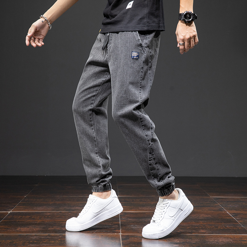 Trendy men's denim cargo pants in casual style, featuring a loose fit and elastic waistband, paired with stylish white sneakers.