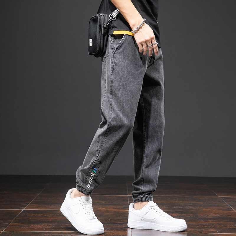 Men's denim cargo pants with a loose fit, styled casually in gray, paired with white sneakers for a trendy look.