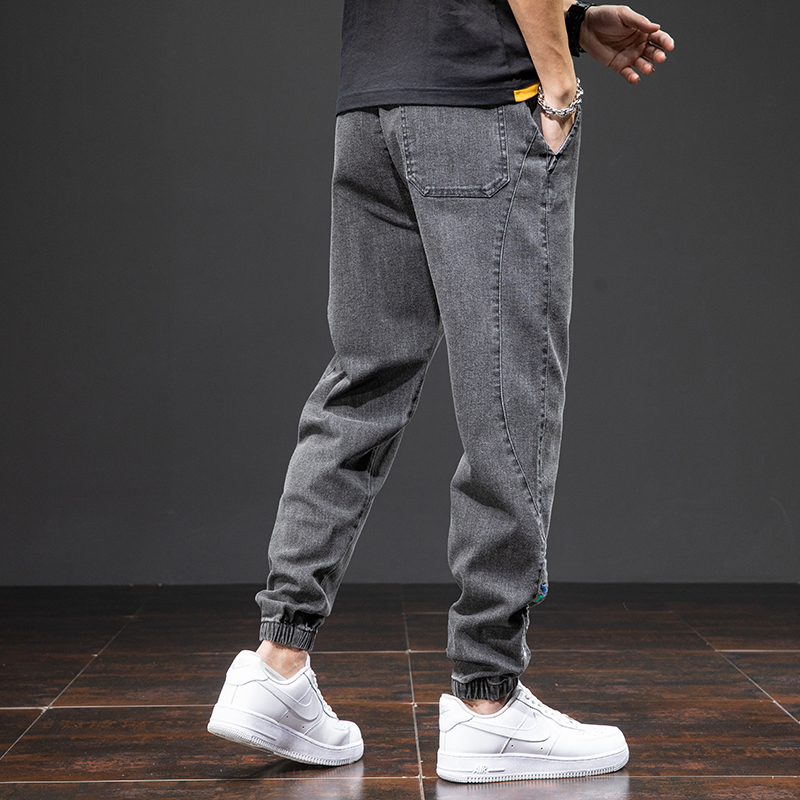 Men's denim cargo pants in gray, featuring a loose fit and elastic waist, styled with white sneakers for a cool casual look.