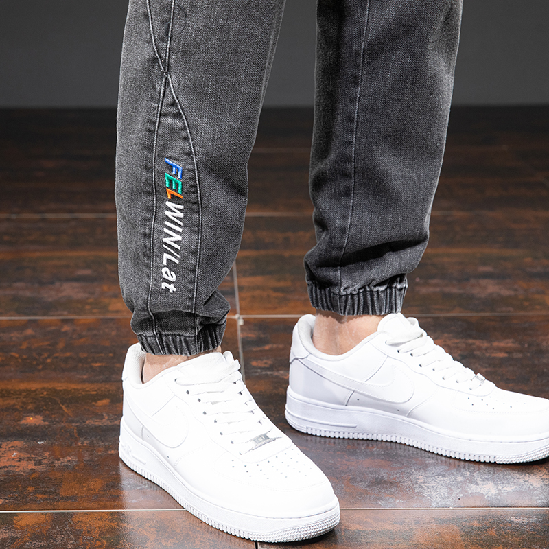Men's denim cargo pants in black with elastic cuffs, paired with stylish white sneakers for a trendy casual look.
