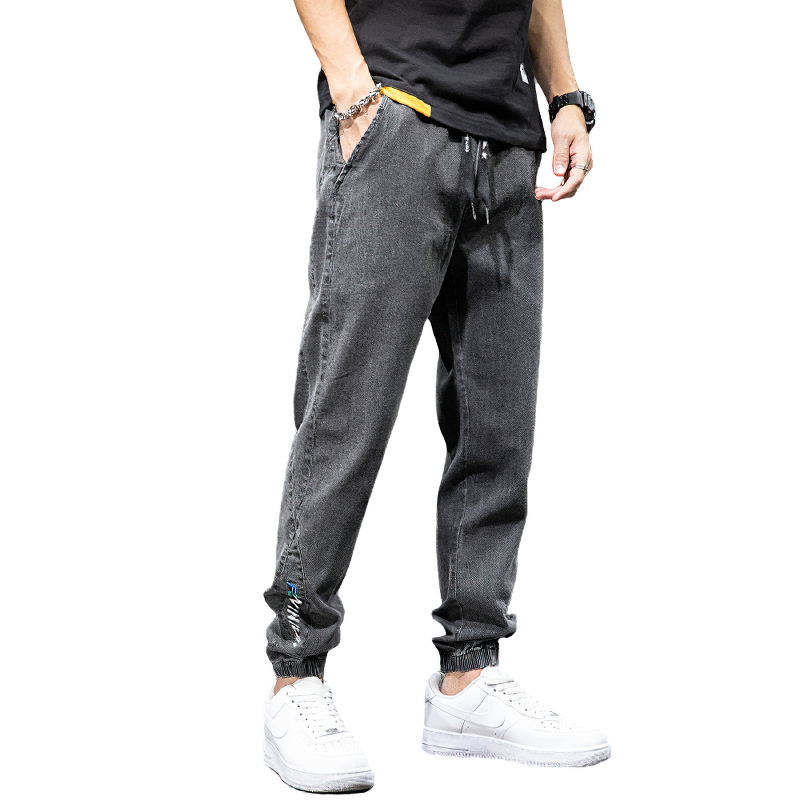 Men's denim cargo pants in grey with elastic waist, perfect for casual style and comfort. Modeled with white sneakers.