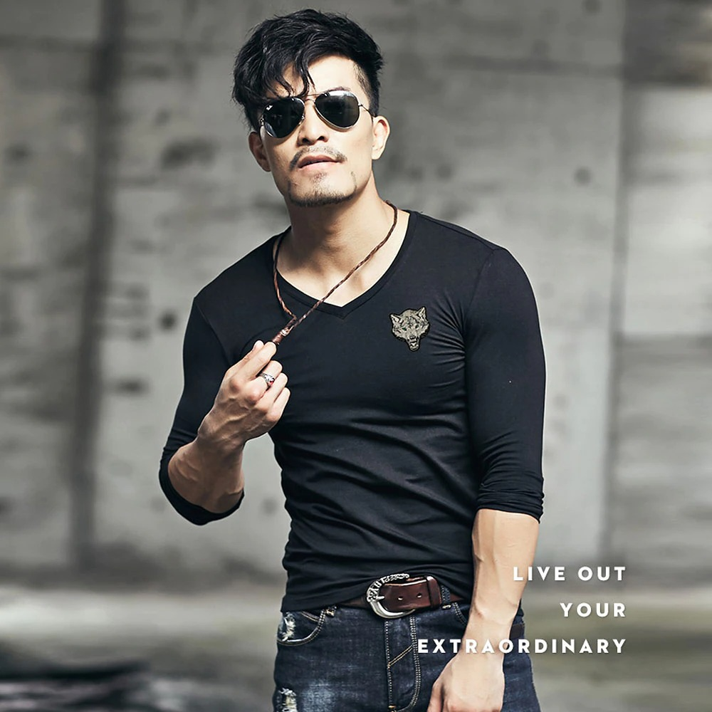 Stylish man in a black v-neck long sleeve t-shirt with wolf embroidery, showcasing trendy fashion and confidence.