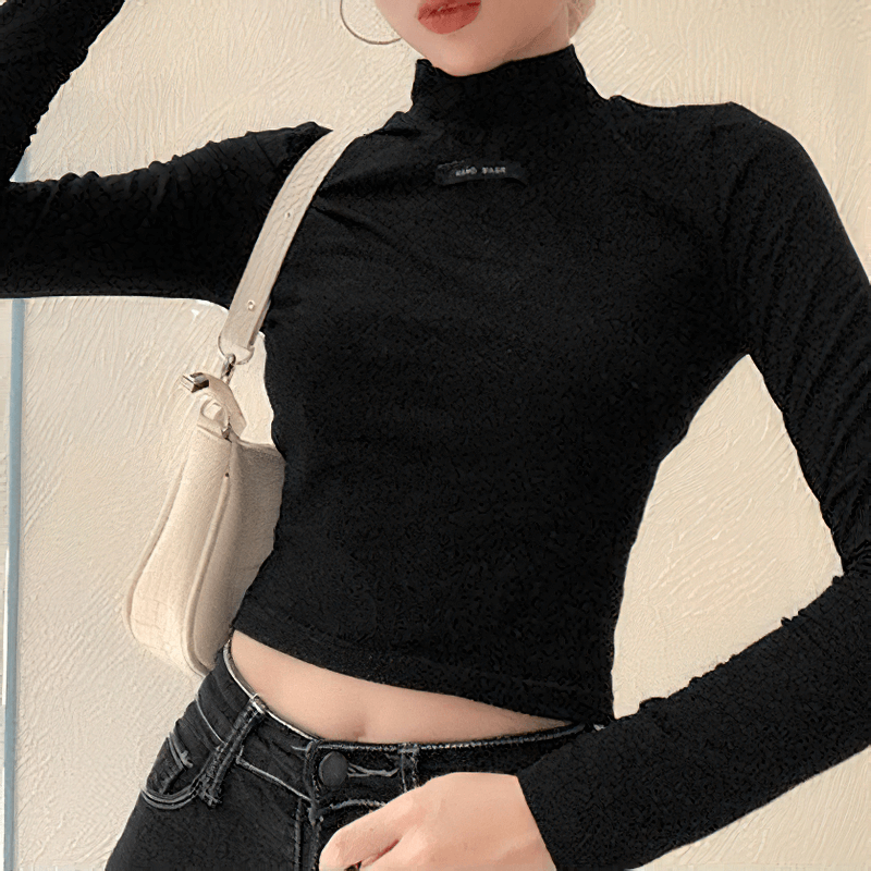 Stylish woman in a black fitted long-sleeve top paired with a trendy handbag, showcasing contemporary fashion.