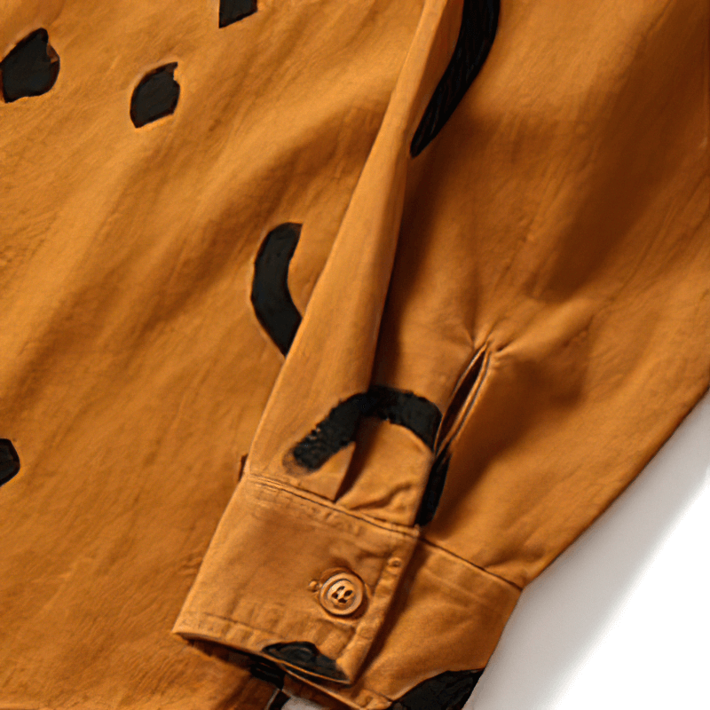 Close-up of a trendy orange cotton shirt with playful black smile print on the sleeve, perfect for casual outings.