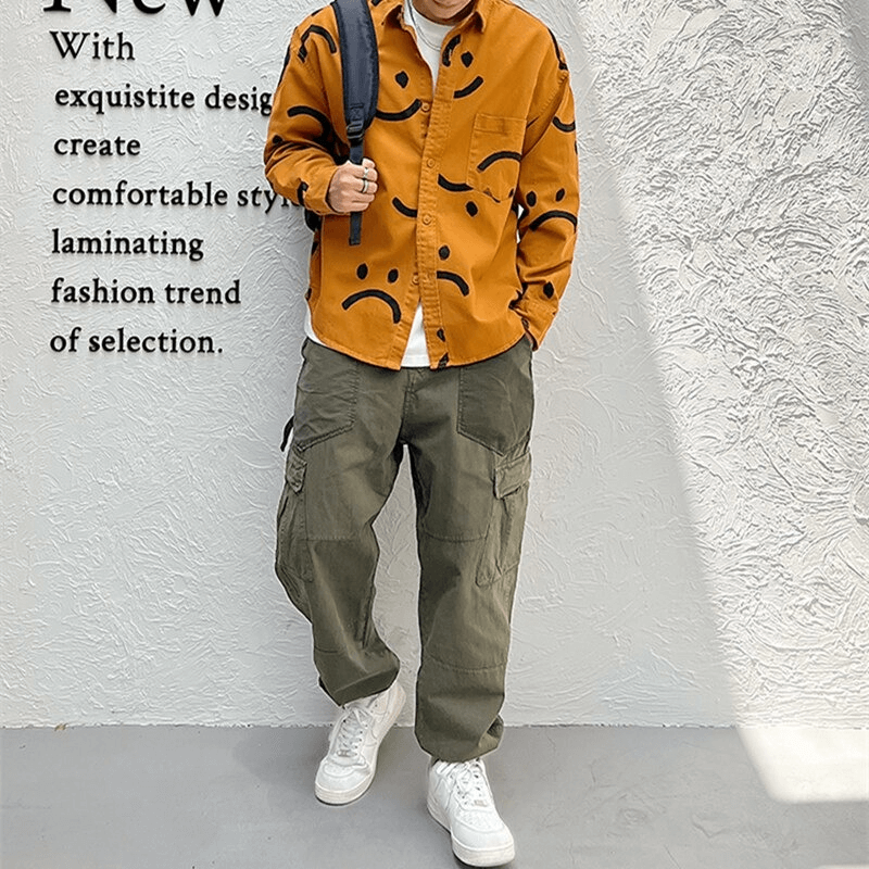 Trendy men's smiley print cotton shirt in orange, paired with casual cargo pants and white sneakers for a stylish look.