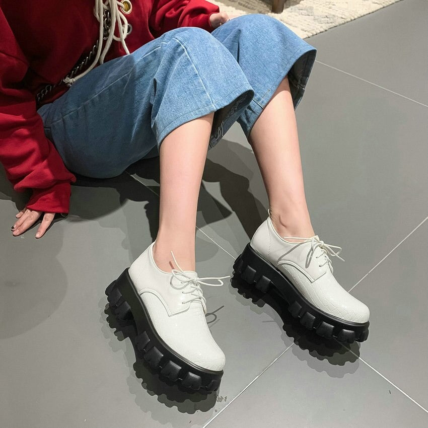Stylish white lace-up platform shoes with chunky black sole, perfectly matching casual denim and sweatshirt outfit.