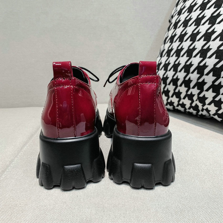 Rear view of stylish red patent leather lace-up women pumps with chunky black sole.