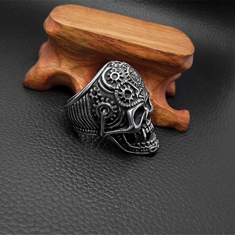 Stainless steel skull ring with intricate design on a wooden display, perfect for punk rock lovers.