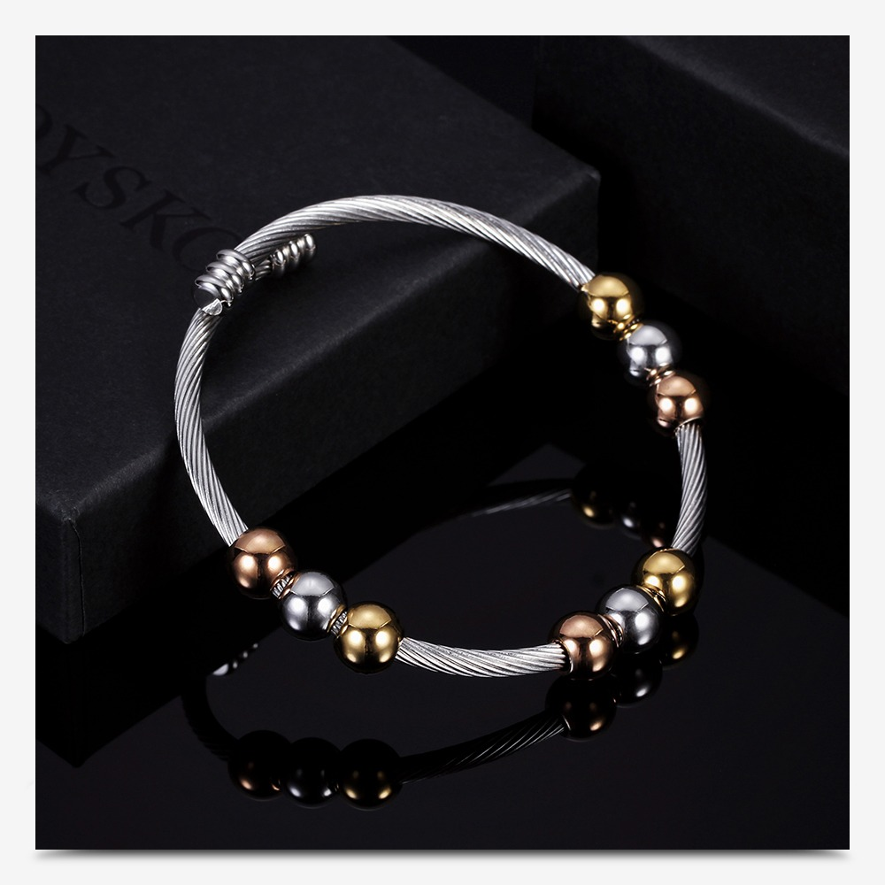 Stainless steel bracelet in gold and silver with stylish round elements on a dark surface.