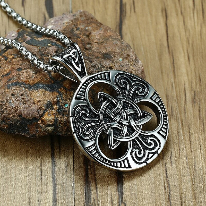 Stainless steel Celtic knot pendant with intricate design, displayed on a rustic stone background, showcasing vintage elegance.