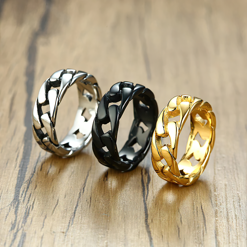 Stylish stainless steel chain link rings in silver, black, and gold on a wooden surface, perfect for unisex fashion.