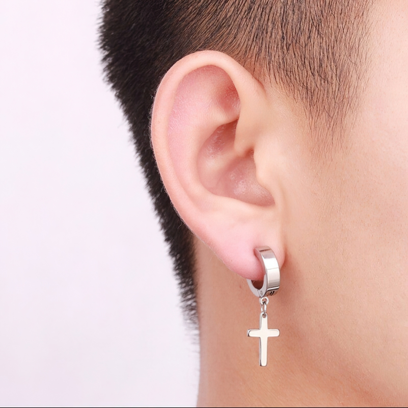 Close-up of a person wearing stainless steel dangle punk earrings with a cross design, perfect for unisex style.