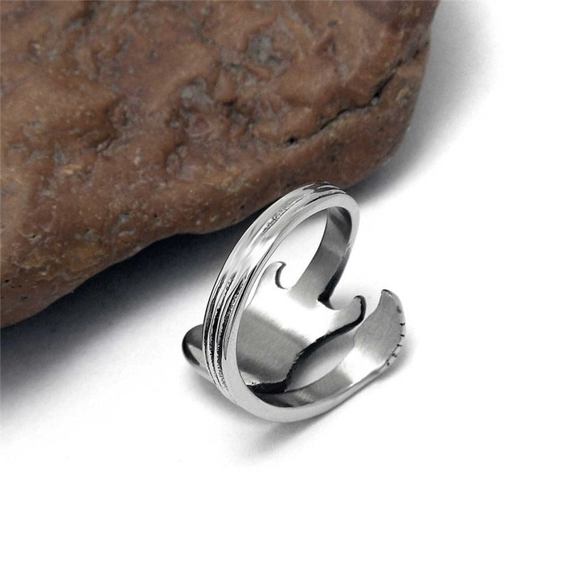 Stylish unisex stainless steel guitar ring resting on a natural rock, perfect for rock musicians and music lovers.