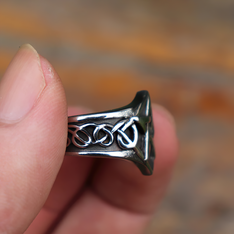 Close-up of a stainless steel pentagram unisex ring held between fingers, showcasing its intricate design.