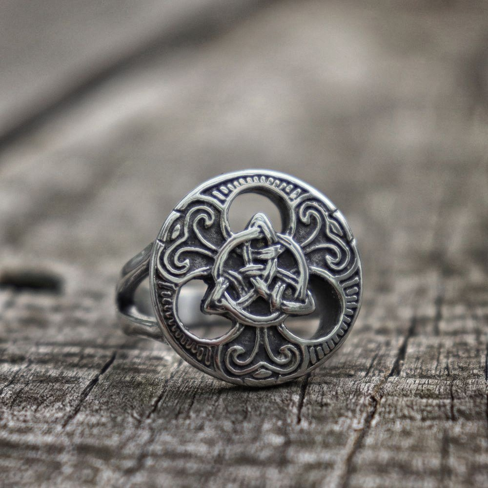 Celtic-style stainless steel ring for men and women on a rustic wooden surface.