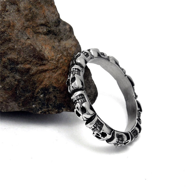 Unique stainless steel round skull ring showcasing a punk retro design on a rocky surface, perfect for alternative fashion.