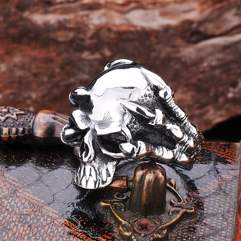 Stainless steel skull ring held by claws, perfect for bikers and rock fans, gleaming and bold accessory.