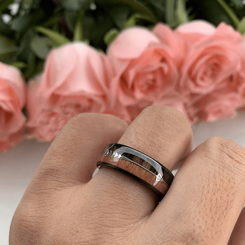Stainless steel vintage ring with arrow and wood pattern worn on hand, surrounded by pink roses.