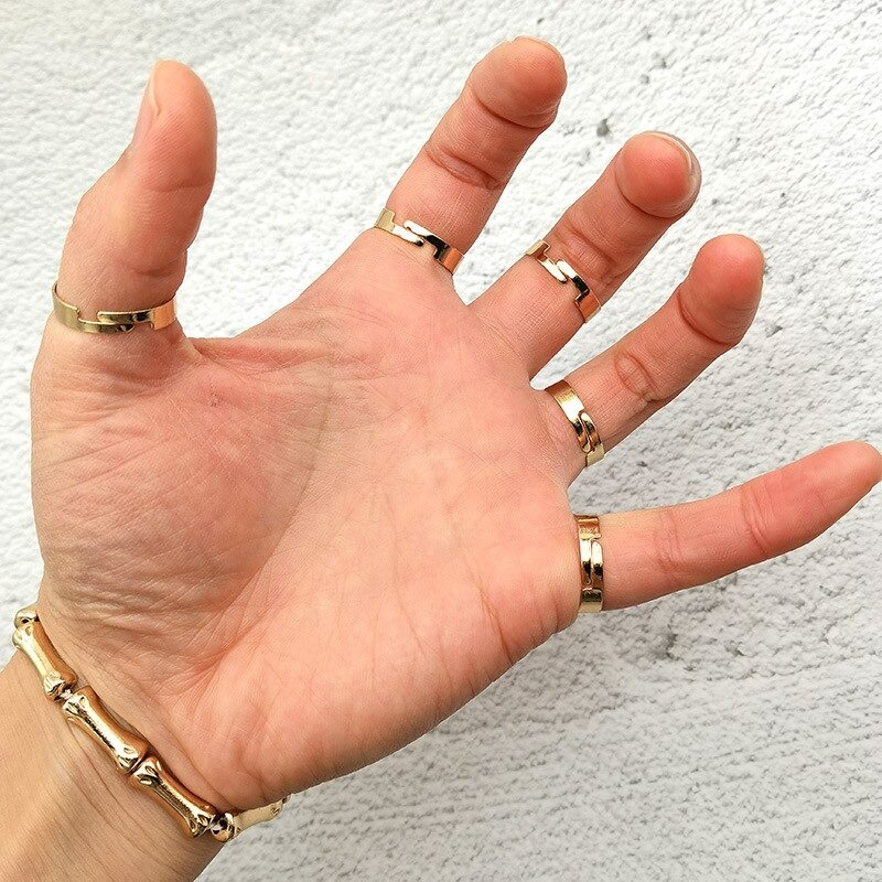 Close-up of a hand adorned with multiple gold rings showcasing unique designs, emphasizing stylish jewelry trends.