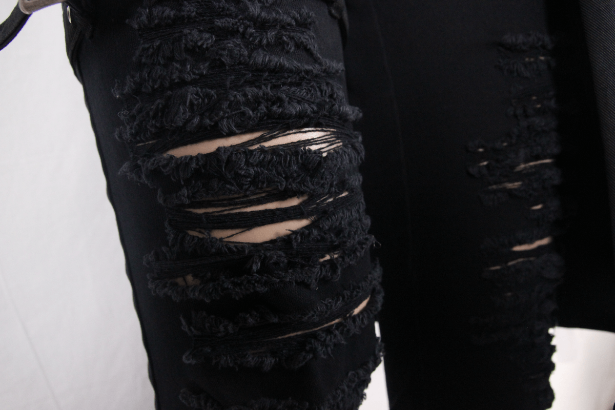 Close-up of black steampunk fashion trousers with stylish torn insert details and kilt holes.