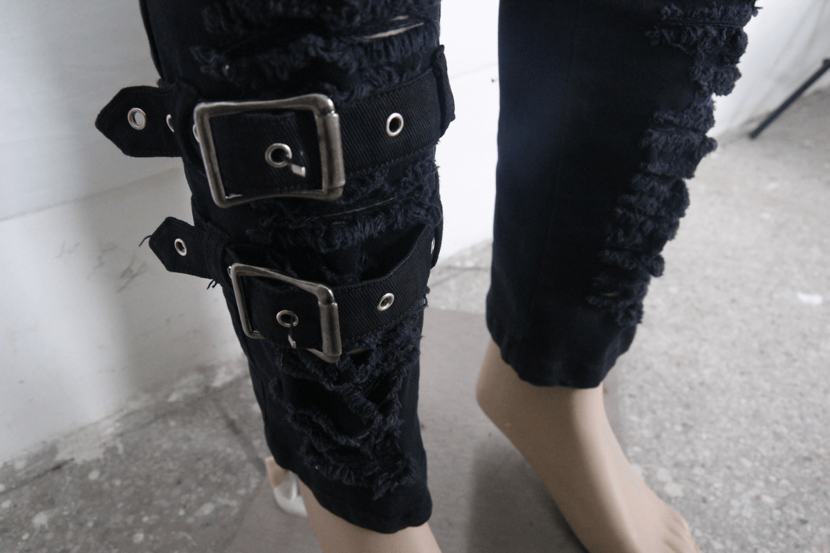 Close-up of steampunk men's black slim pants with kilt holes and stylish buckle straps.