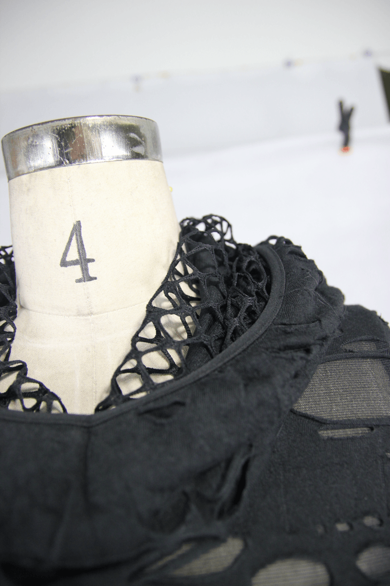 Close-up of a steampunk women's black long sleeve hoodie with unique leather straps and torn inserts.