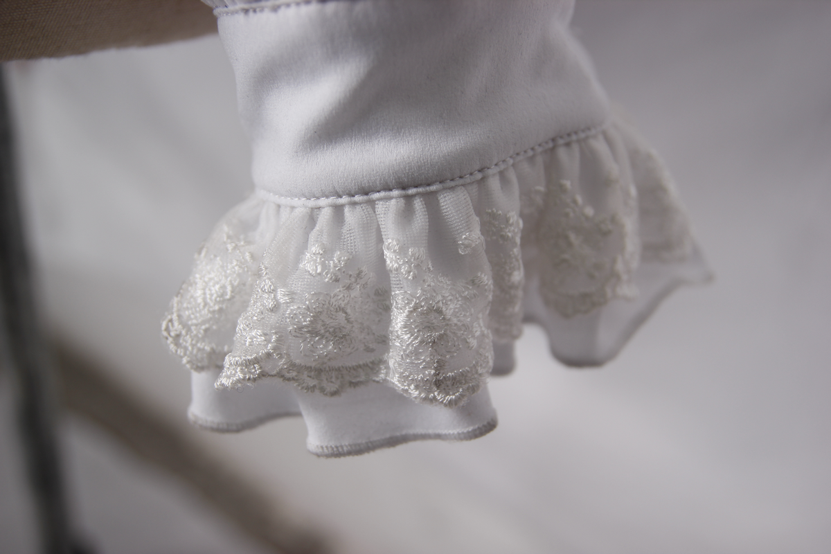 Close-up of a vintage white shirt's ruffled cuff with elegant embroidery, perfect for gothic fashion lovers.