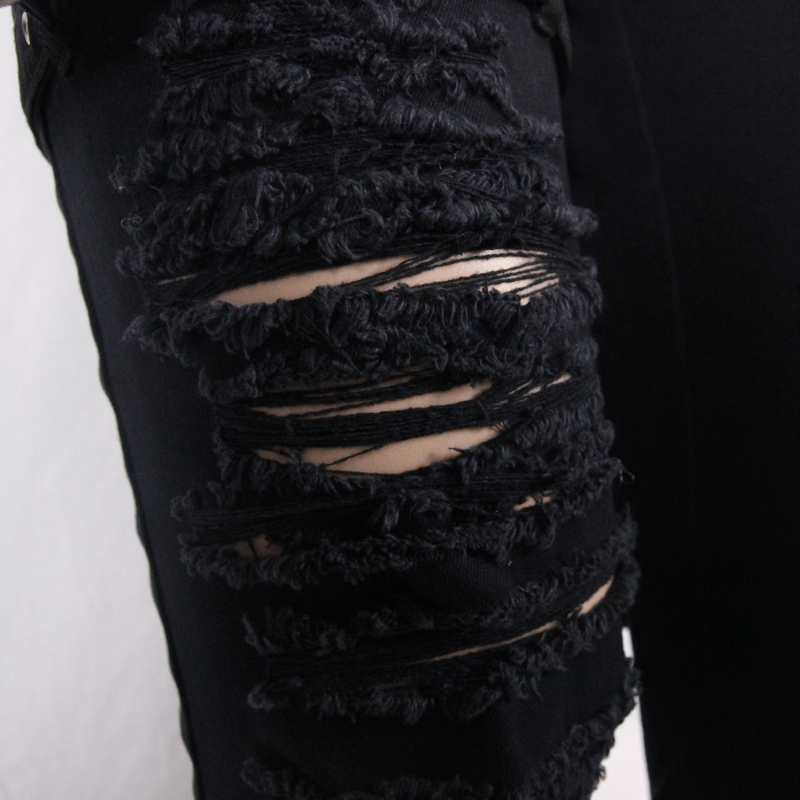 Close-up of ripped black gothic pants showcasing unique distressed design and textured fabric details.