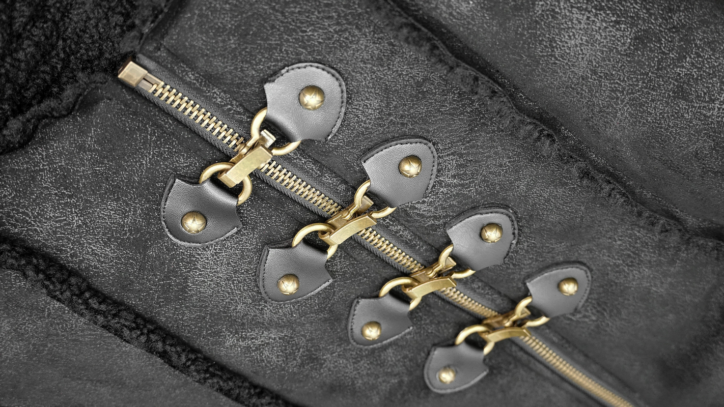 Close-up of the zipper and detailing on a steampunk men's long winter coat with fur inserts.