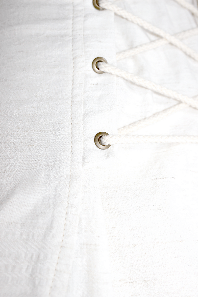 Close-up of lace-up detail on a steampunk women's white blouse with drawstrings and vintage design.