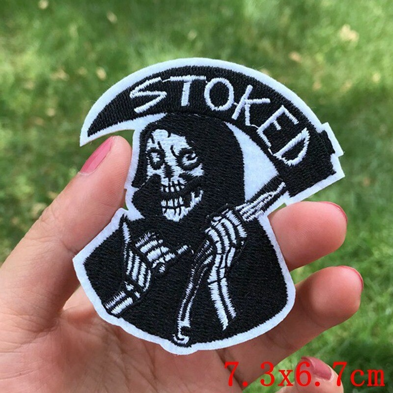 Stoked Reaper fusible rock patch held in hand, featuring a skeleton design, perfect for jackets and bags, 7.3x6.7cm.