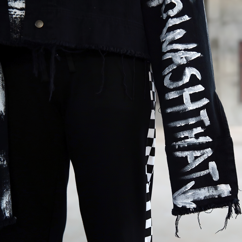 Close-up of a men's graffiti print jeans jacket, showcasing bold lettering and stylish frayed edges for trendy streetwear.