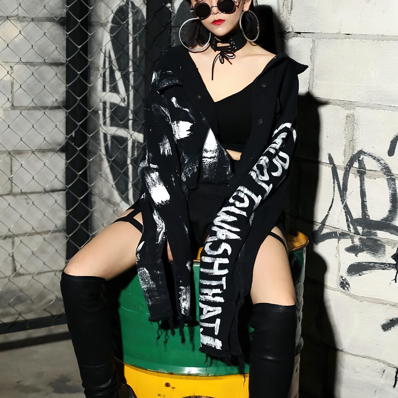 Trendy women wearing a graffiti print jeans jacket, paired with stylish black boots in a streetwear setting.