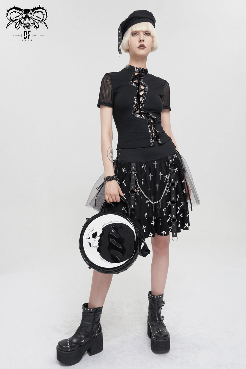 Gothic fashion model wearing black outfit with crescent moon and skull handbag, showcasing edgy style.