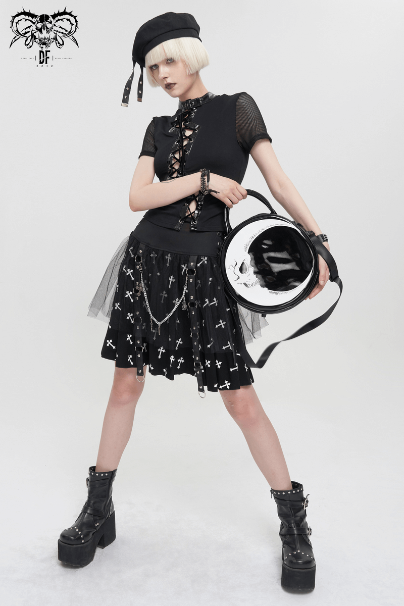 Gothic woman in lace-up top, cross-patterned skirt, and stylish crescent moon skull handbag, exuding edgy fashion.