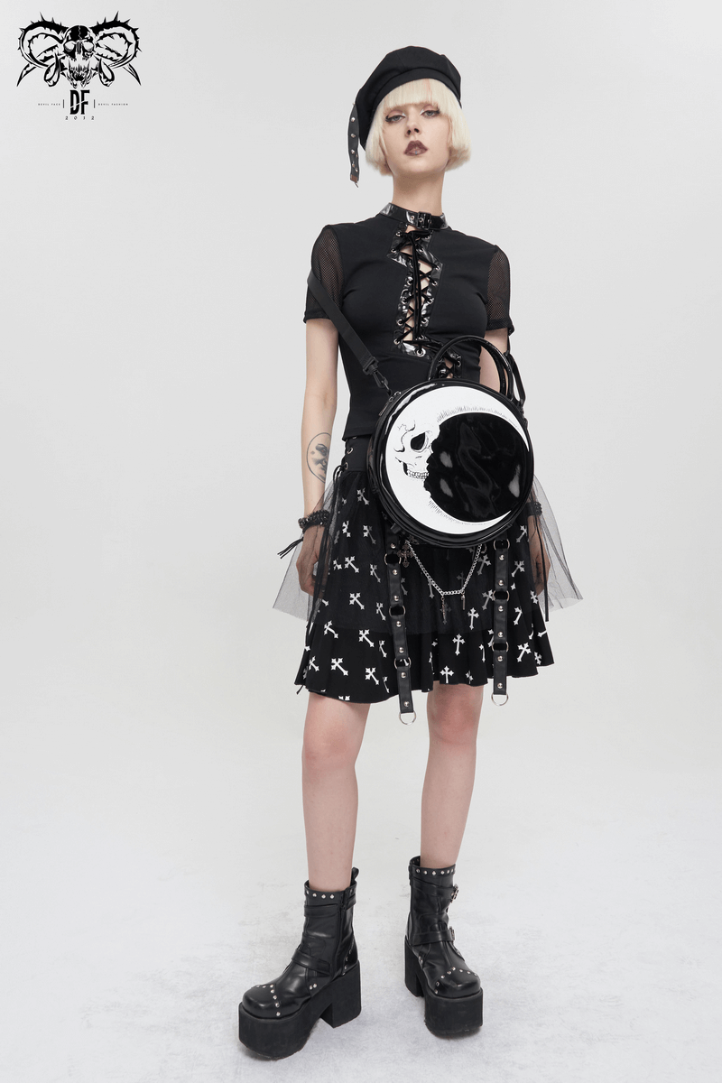Stylish woman in gothic outfit with crescent moon skull handbag and chunky boots, perfect for a trendy gothic look.