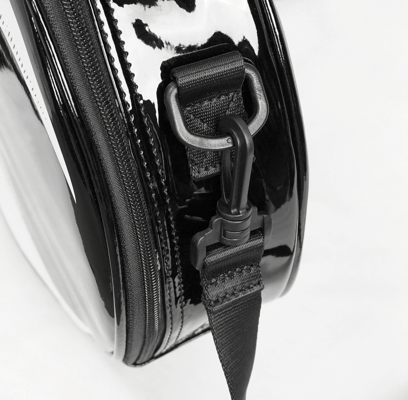Close-up of a glossy black handbag with a stylish zipper and strap detail, showcasing its chic design.