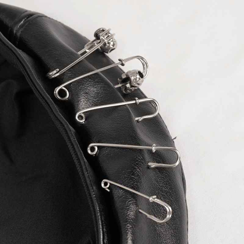 Close-up of stylish faux leather beret hat featuring decorative silver pins for a punk-inspired look.