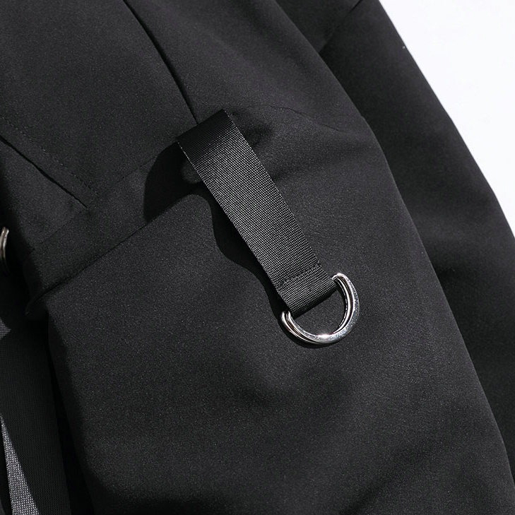 Close-up of a black men's military streetwear jacket showcasing unique ribbons and pockets.