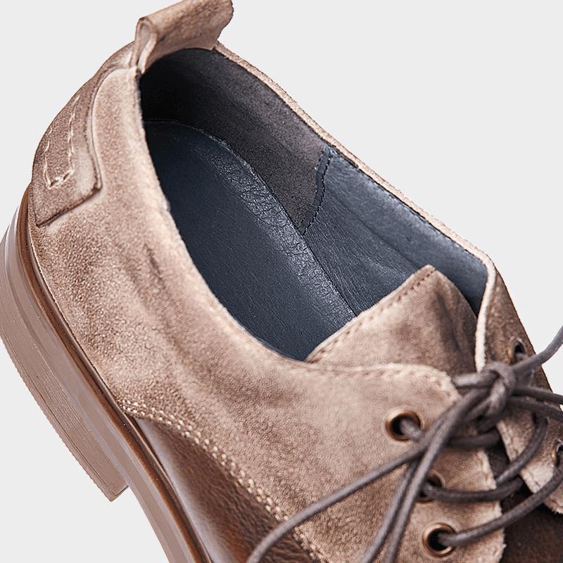 Close-up of stylish lace-up cowhide cowboy shoes featuring a soft brown suede finish and casual round toe design.