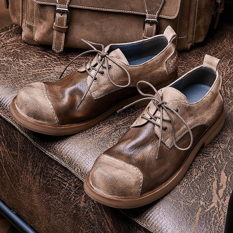Stylish lace-up cowhide cowboy shoes for men in brown on textured surface, perfect for casual outfits.