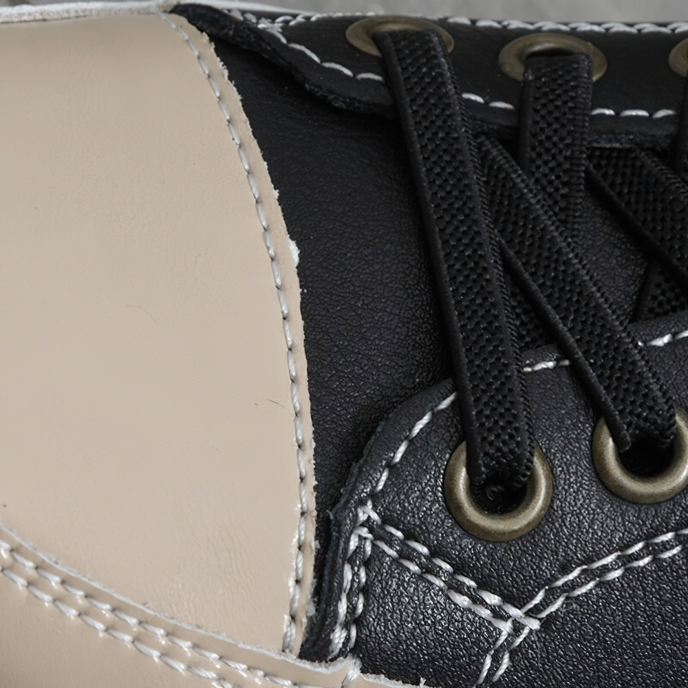 Close-up of stylish ladies genuine leather sneakers in black and beige with detailed stitching and laces.