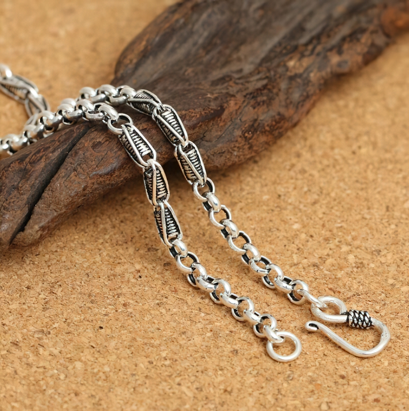 Stylish sterling silver link chain necklace for men and women placed on natural wood surface.